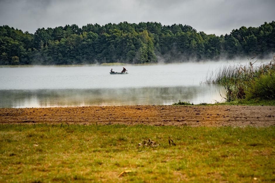 Angler on a calm lake at dawn